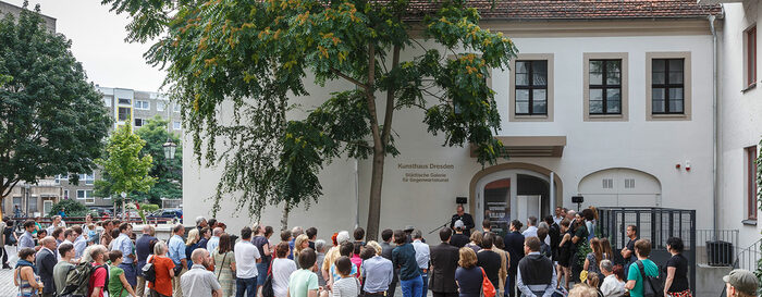 Menschen stehen vor einem weißen Gebäude mit der Aufschrift "Kunsthaus Dresden"