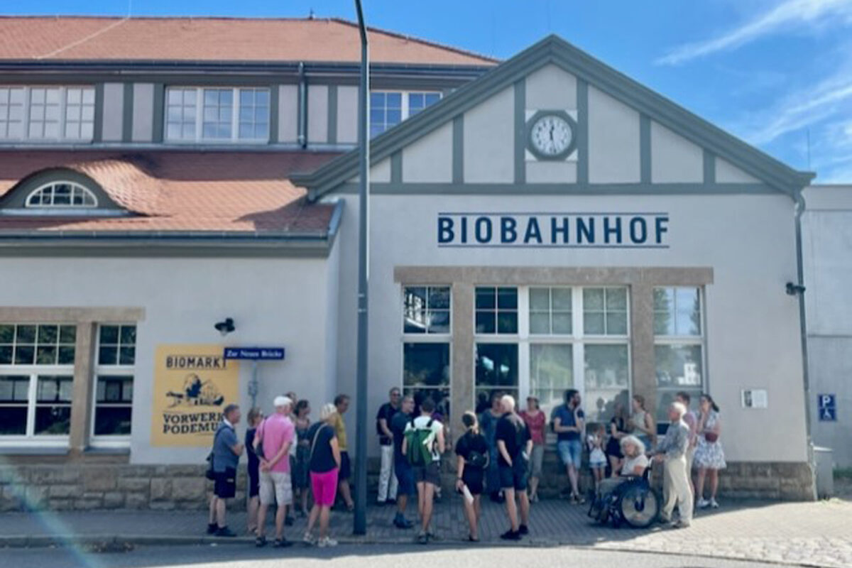 Menschengruppe, die an einer Führung teilnimmt, vor dem Bahnhofsgebäude Dresden-Klotzsche