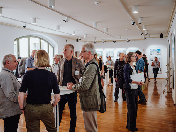 Im Kunstfoyer sind Tagungsteilnehmende im Gespräch oder betrachten die Ausstellung