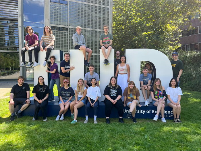 Gruppenfoto von Studierenden vor dem Logo der TU Dresden