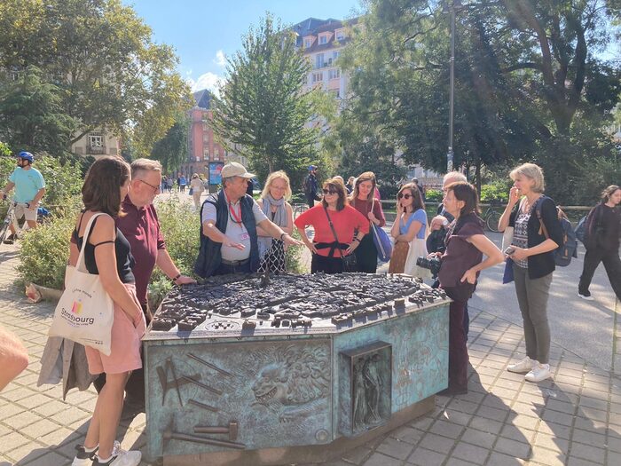 Eine Gruppe von Personen stehen im Zentrum von Straßburg und hören einem Touristenguide zu