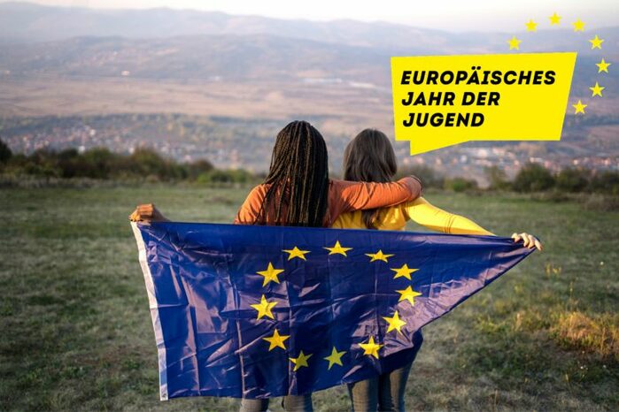 Zwei Jugendliche mit der Europafahne vor einer Landschaft