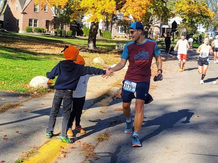 Ein Marathonläufer und zwei Kinder mit Kürbismützen