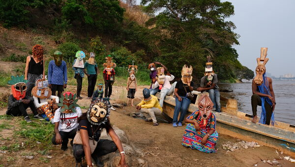 Menschengruppe mit bunten Masken beim Workshop am Ufer