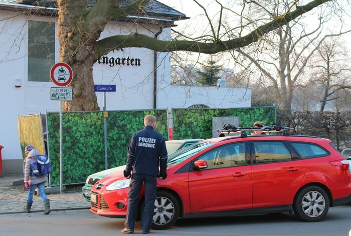 Mitarbeiter des Ordnungsamtes kontrolliert vor einer Schule ein Auto