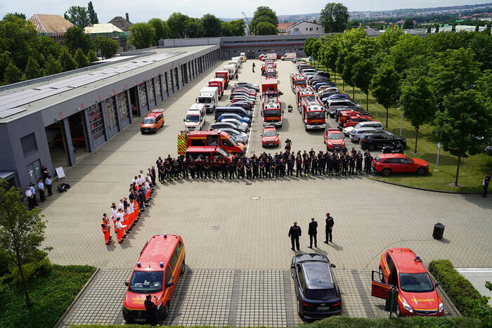 Einsatzkräfte der Feuerwehr auf einem Parkplatz mit Fahrzeugen der Feuerwehr