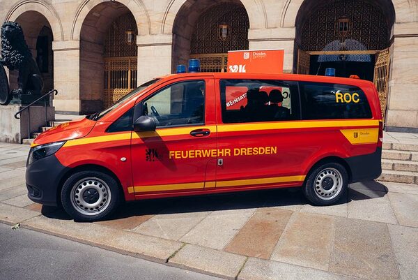 Roter Transporter von der Seite mit Blaulicht und der Beschriftung "Feuerwehr Dresden"