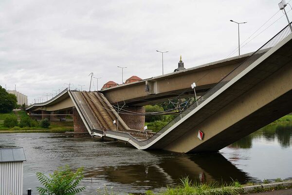 Brücke, die in den Fluss hängt und Schienen, die in der Luft darüber hängen