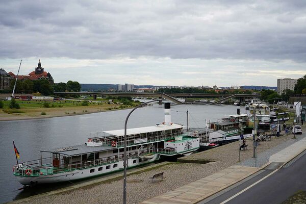 Vorn ein Schiff auf einem Fluss und hinten eine Brücke, die in den Fluss hängt