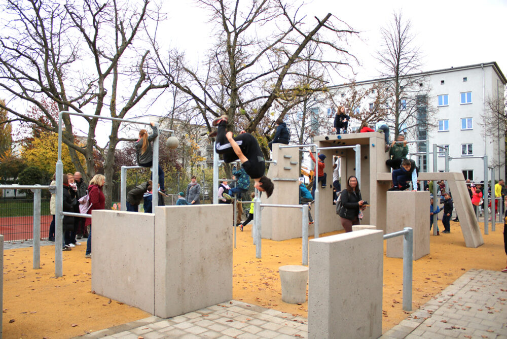 Menschen springen und klettern über Hindernisse aus Beton.