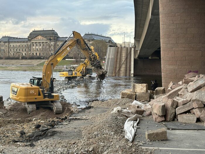 Bagger stehen auf einem Damm in der Elbe und reißen diese ab