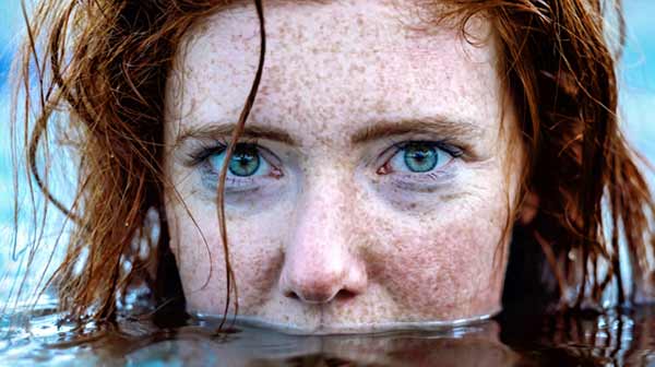 Rothaarige Frau mit großen grünen Augen im Wasser