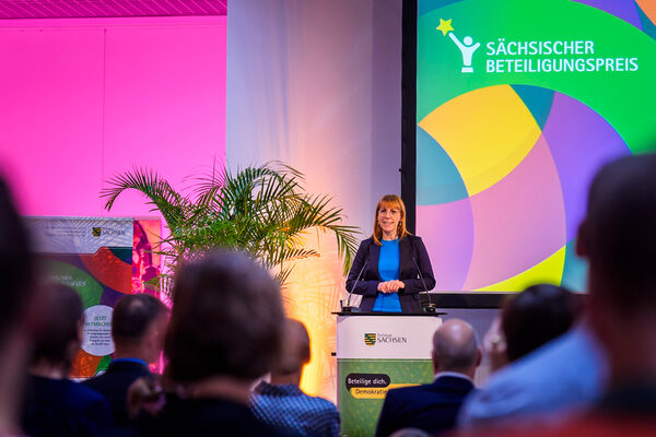 Frau Staatsministerin Katja Meier steht auf einem Podium und spricht zum Publikum