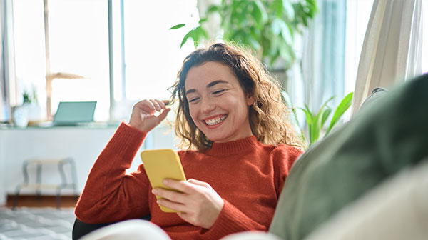 Mädchen mit gelbem Handy in der Hand und lächelnd aufs Handydisplay