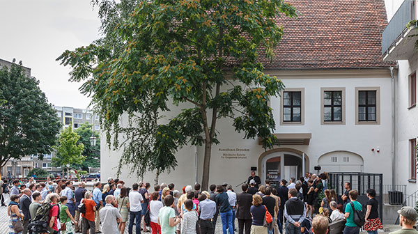 Menschen stehen vor einem weißen Gebäude mit der Aufschrift 