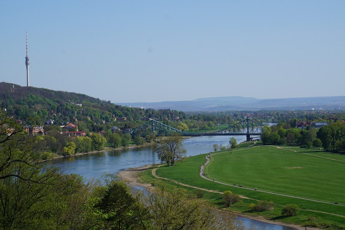 Die Elbwiesen in Blasewitz und die Loschwitzer Elbhänge sowie das Blaue Wunder. Im Hintergrund sind entfernt die Silhouetten von Osterzgebirge und Sächsischer Schweiz zu sehen.