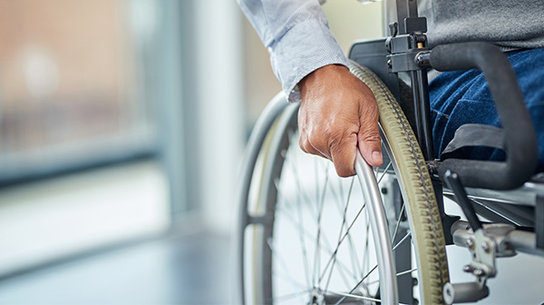 Rollstuhl mit Fokus auf ein Rad, an dem die Hand des Rollstuhlfahrers ist