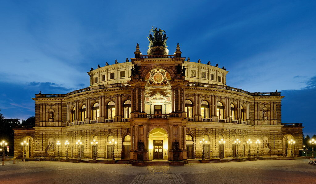 Die Semperoper am Theaterplatz mit festlicher abendlicher Beleuchtung.